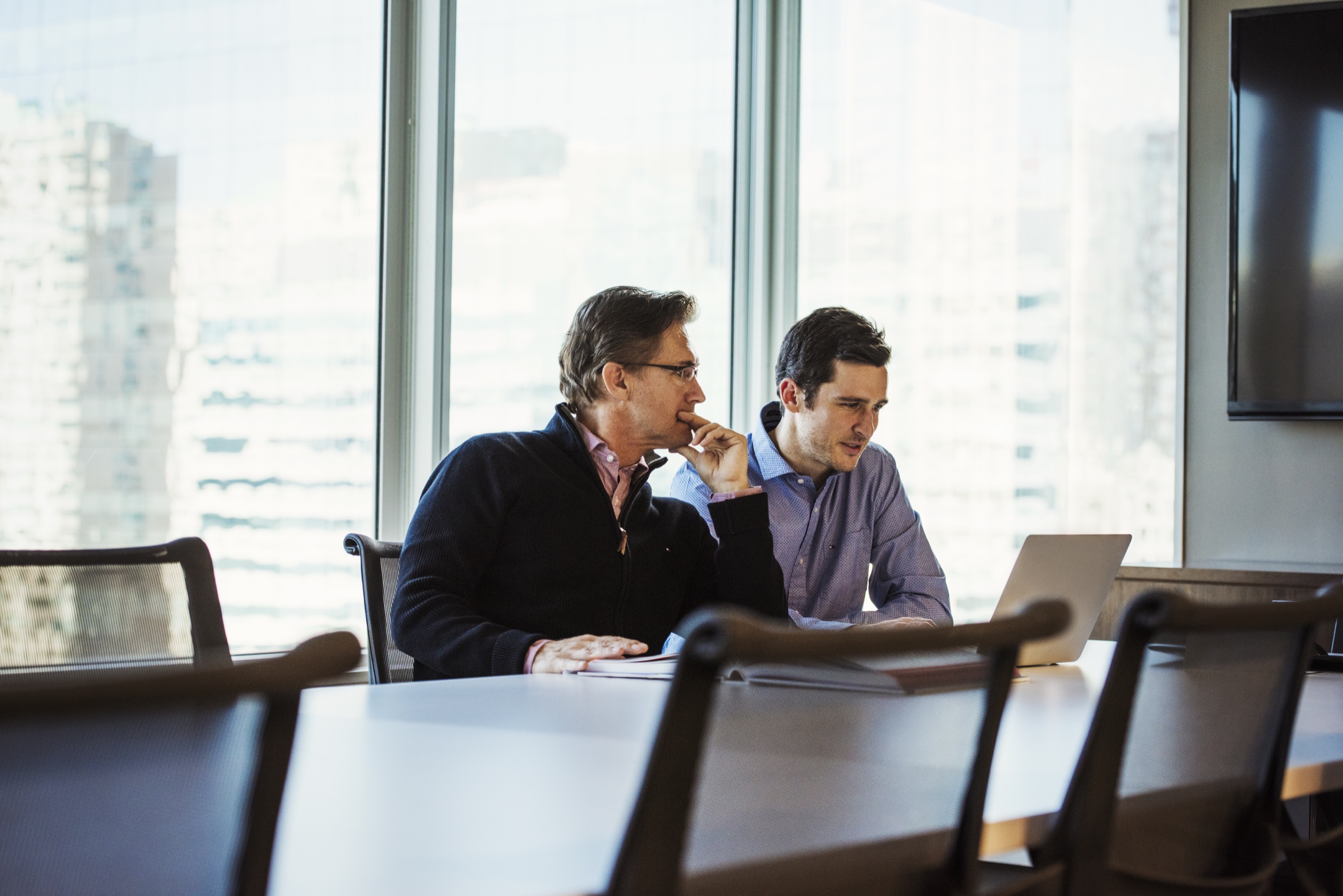 Two professionals reviewing a financial plan together at a laptop in a sunlit office.